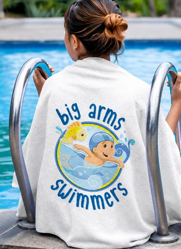 Big Arms Swimmers swim school logo printed on towel featuring cartoon boy swimmer and fish mascot for kids swimming lessons